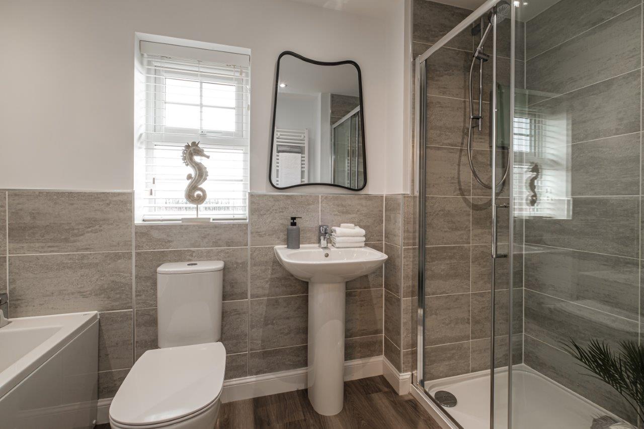 Photo of a grey tiled bathroom with shower, bath and window