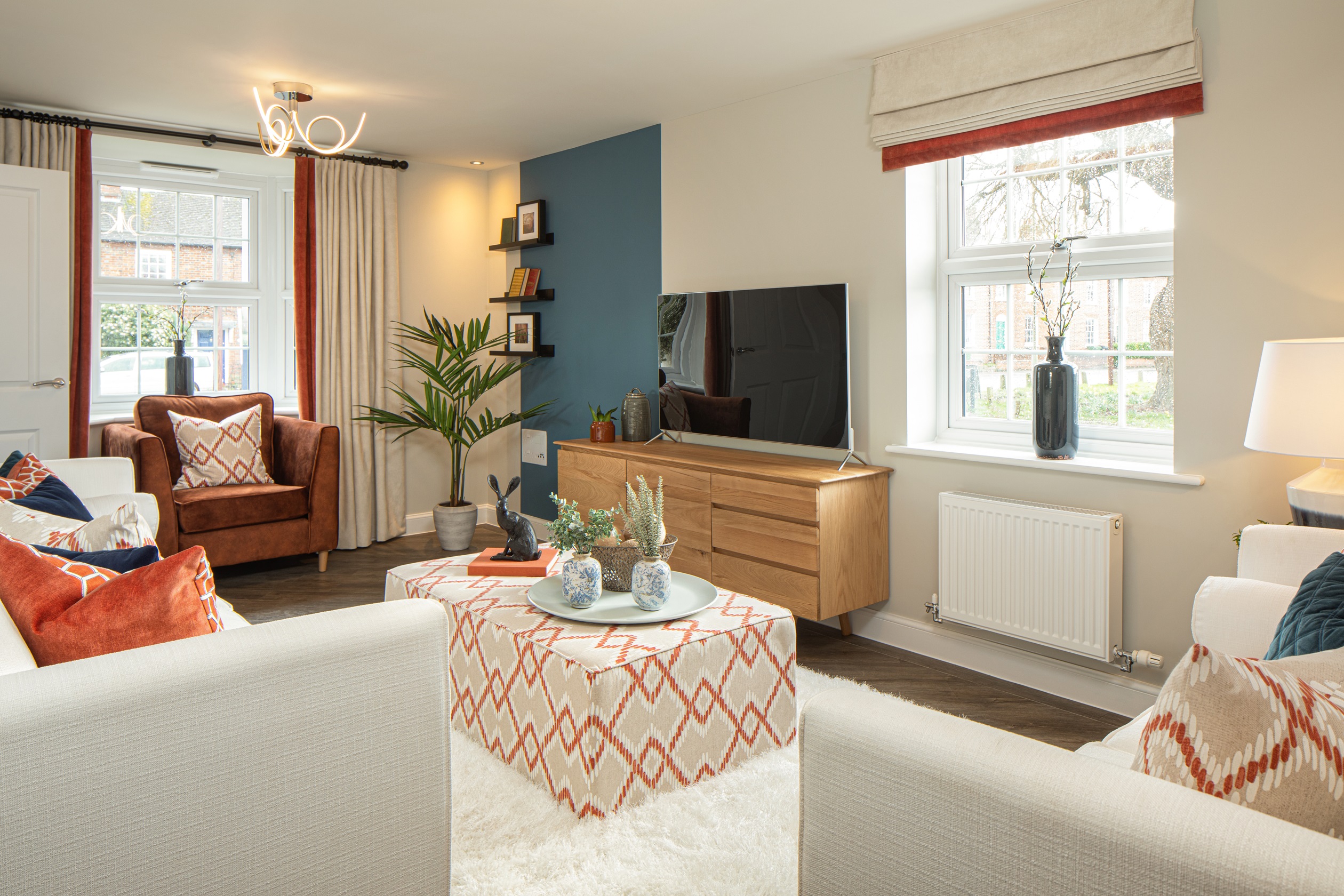 Dual aspect lounge with two cream sofas and a rust armchair