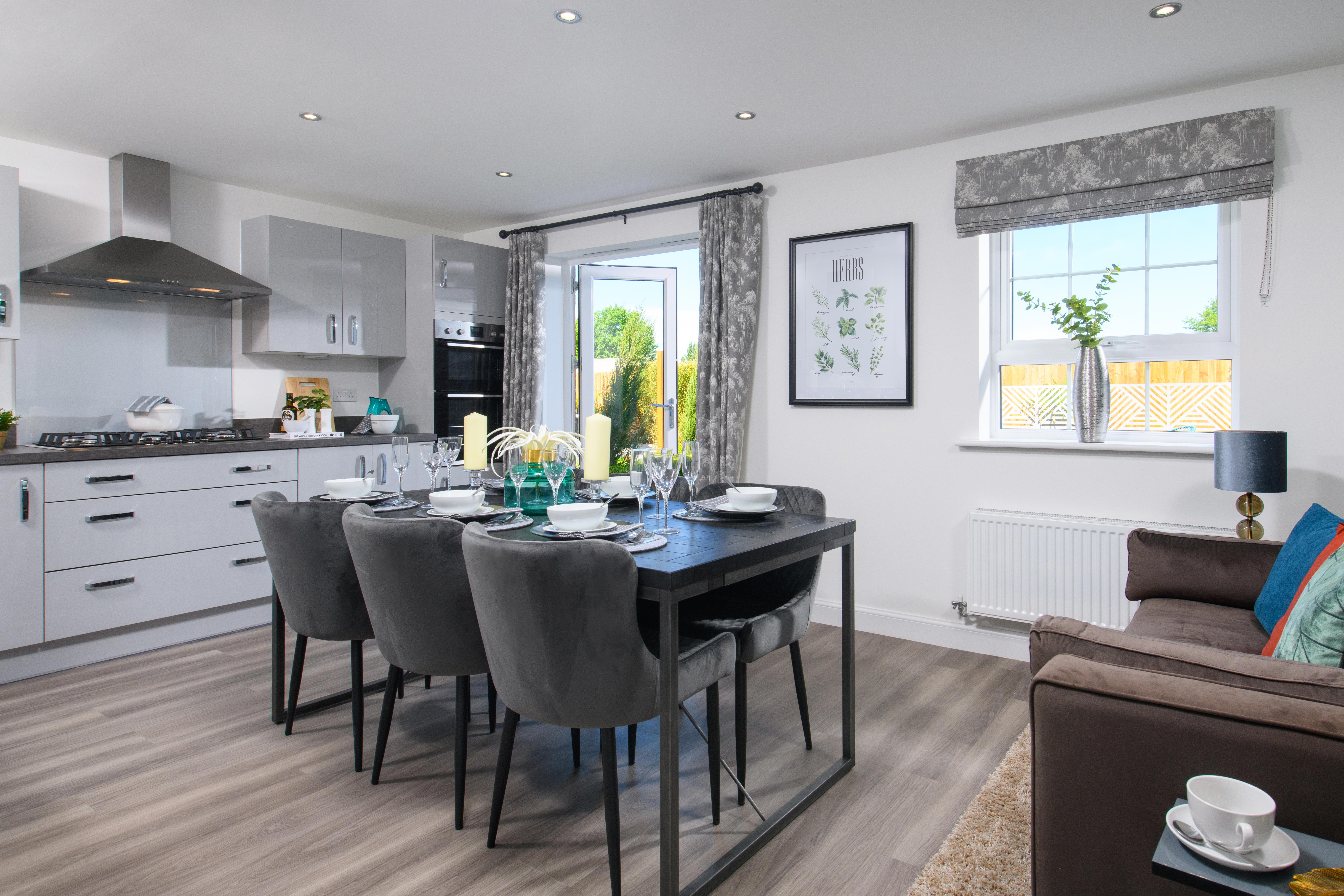 Open-plan kitchen/diner with integrated appliances and French doors leading onto garden in Ingleby style home