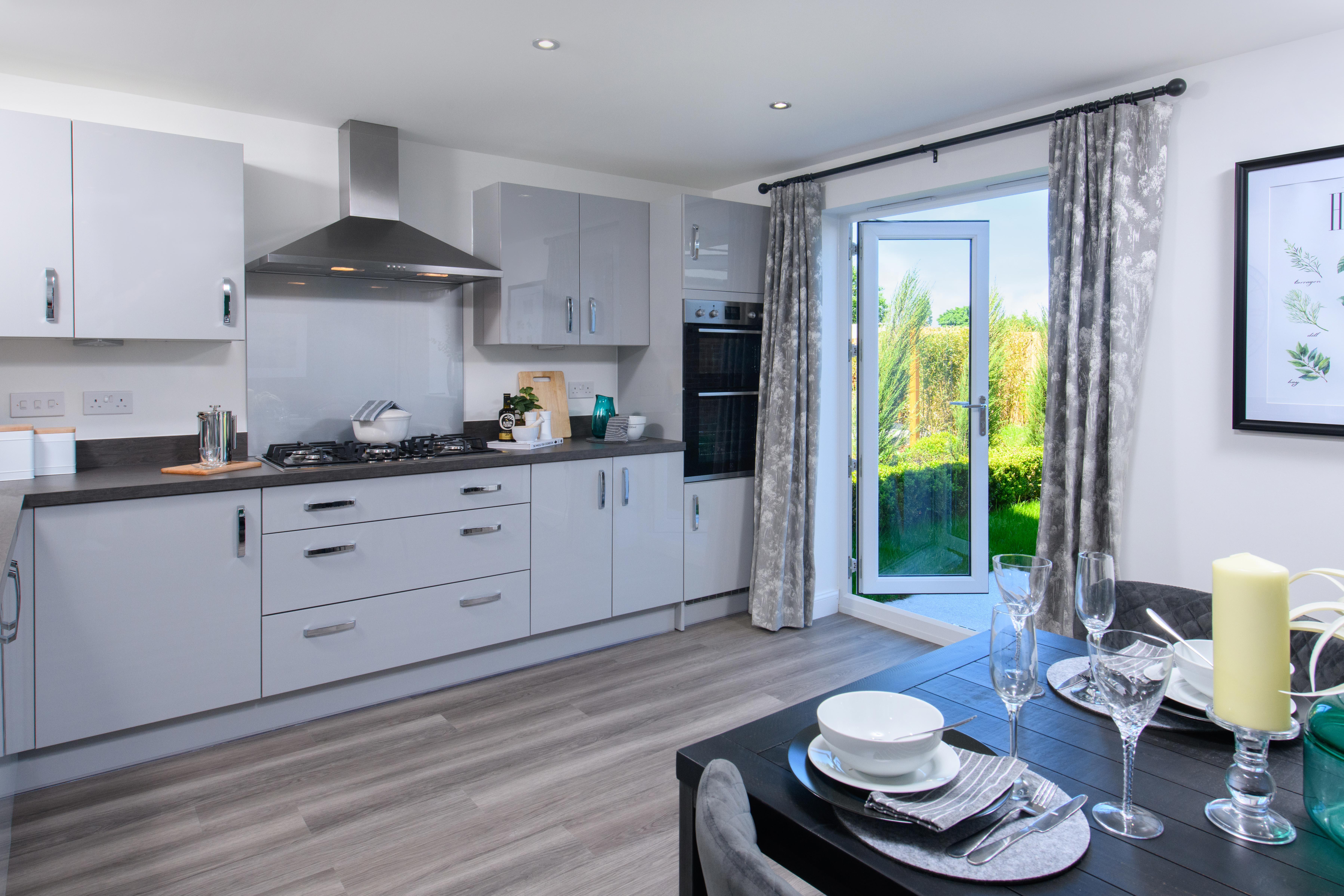 Open-plan kitchen/diner with integrated appliances and French doors leading onto garden in Ingleby style home