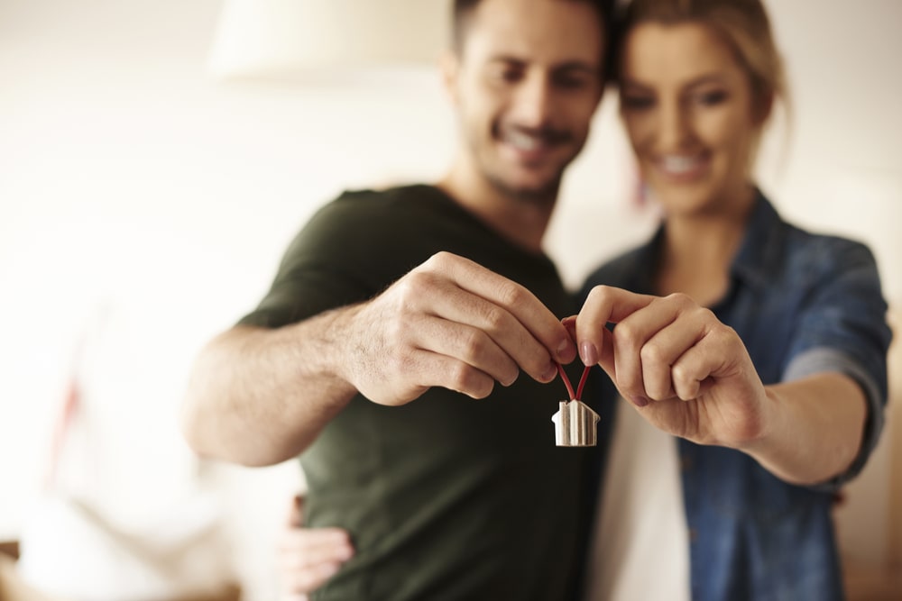 a couple with a keyring on the keys to their first home