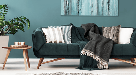 Dark green sofa with cushions and throws