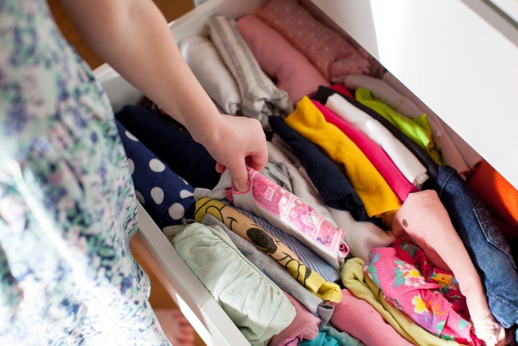 photograph of person grabbing clothing items in organised drawer