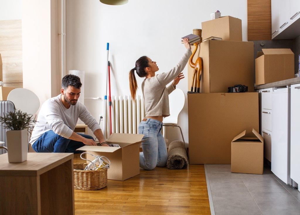 Image of young couple decluttering and organising their items into cardboard boxes